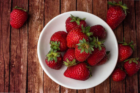 Fresh strawberries on a dark wooden table on a plate
