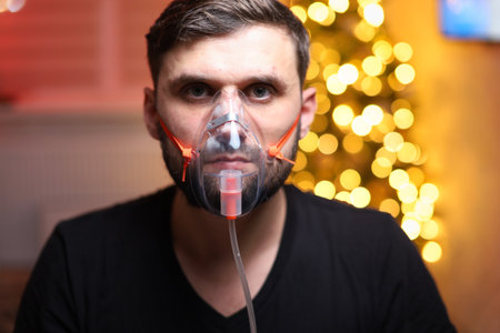 a man wearing a lung inhalation mask in front of Christmas lights