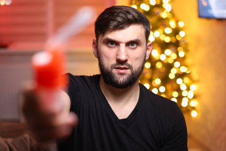 a man holds a device for lung inhalation against the background of Christmas lightsの写真素材
