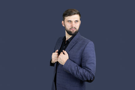 a man with a beard and a blue suit presses his fist to his head showing emotions of pain
