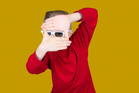 a child in 3D glasses puts his hand to his ear and tries to hear somethingの写真素材