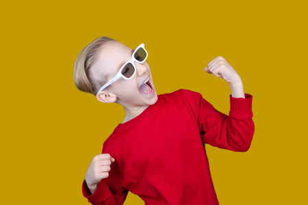 a child in 3D glasses puts his hand to his ear and tries to hear somethingの写真素材
