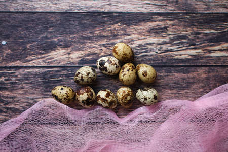 quail eggs in a pink basket on a wooden table top view, eggs for the Easter holidayの写真素材
