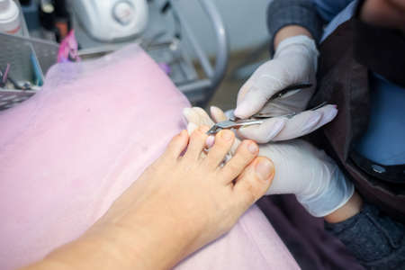 The girl master of nail service works with the client