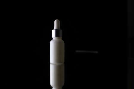 On a white bottle with an eyedropper drops of waterの写真素材