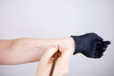 A girl's hand in a black glove holding a tattoo machine