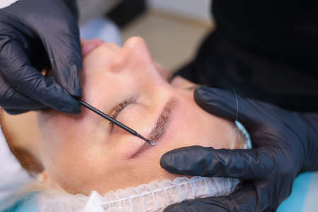 Tattoo Artist combs client's eyebrow with microbrashの写真素材
