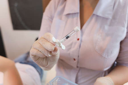 The cosmetologist holds in his hands a filler for the introduction of hyaluronic acid injections...