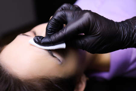 the tattoo artist prepares for the procedure of permanent makeup wraps the pigment holder with a...