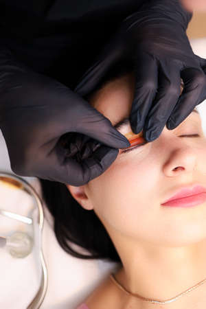 close-up of the hands of the master of lamination of cilia, the master performs the procedure by...