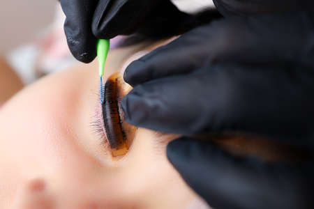 close-up of the master's hands combing the colored cilia with a special comb for eyelashes