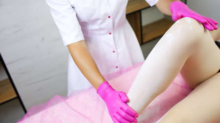 close-up of the hand of the sugar epilator, which also holds the client's leg, already covered in powder, to retreat and work with the sugar.の写真素材