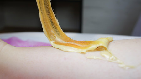 close-up of a master holding a sticky sugar paste in which the hair is stuck after removal