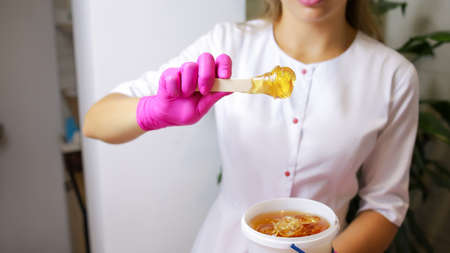 the master of sugar hair removal and removal of unwanted hair with wax stands in front of the client and works with the hand area removing unwanted hair on itの写真素材