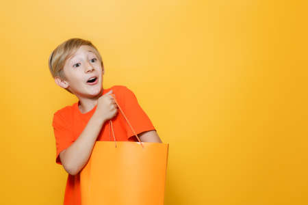 the boy has put his hand in an orange paper bag and is happy