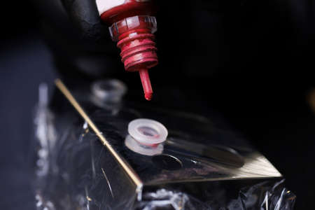 close-up of the master dripping pigments from a jar into a plastic capsule for stirring the tattoo...
