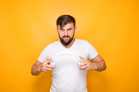 the man holds out the headphones to put them on his head.