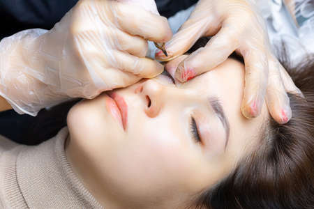 tattoo artist in the process of working on permanent eyelid makeupの写真素材