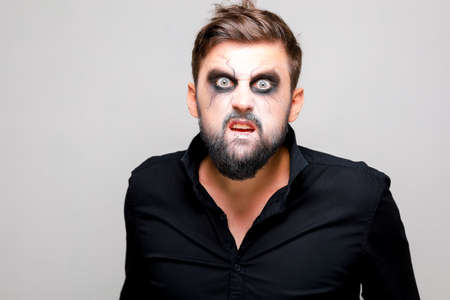 Portrait of a man with a beard and a menacing look with undead-style makeup on All Saints' Day on October 31の写真素材