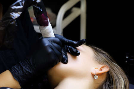 close-up of the lips of a young model who has a tattoo on her lips made up to the middleの写真素材