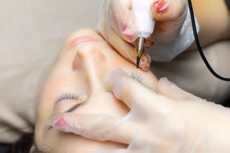 tattoo artist in the process of working on permanent eyelid makeupの写真素材