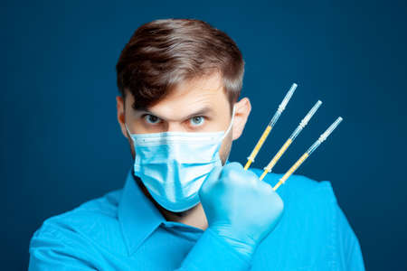 A doctor in a medical mask and gloves, in a blue uniform, shows a thumb upの写真素材