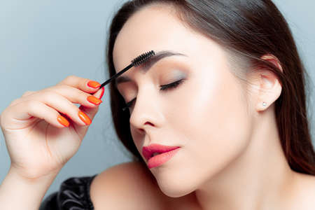 a young girl model holds a makeup brush in front of her with two handsの写真素材