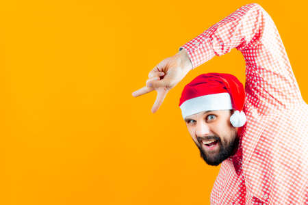 a man in New Year's hats of Santa Claus and a red checkered shirt is attentively examining New Year's toys - a ball of gold color.の写真素材