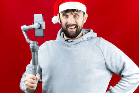 a man dressed in Christmas clothes is holding a selfie stick with a phone attached to it he is taking a selfieの写真素材