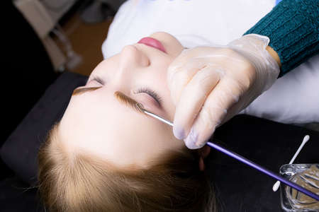the blonde model lies on the procedure of eyebrow coloring with paint after lamination and long-term...
