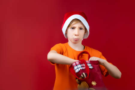 a boy in a Santa hat rummages in a Christmas bag in search of giftsの写真素材