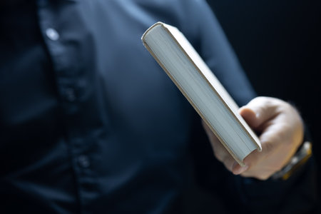 a man in black clothes keeps a thick book at his fingertieの写真素材