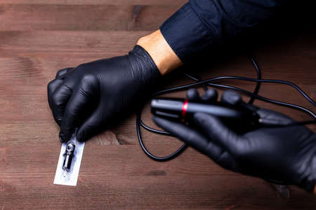 the hands of the permanent makeup master in black medical gloves took a disposable cartridge for...