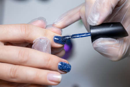 the nail service master does a manicure distributes gel polish to apply it to the nailの写真素材