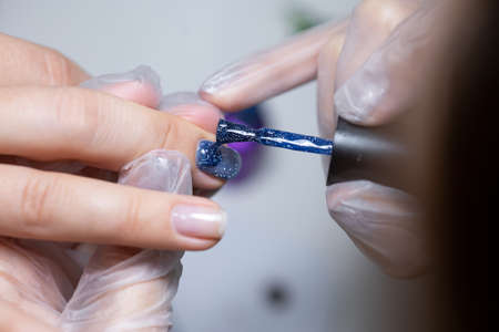 the nail service master does a manicure distributes gel polish to apply it to the nailの写真素材