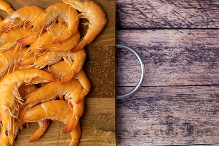 on a wooden table there is a plate made of wood with shrimp on itの写真素材