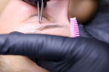 plucking unwanted eyebrow hairs after laminating the eyebrows with tweezers