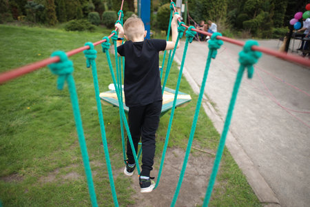 view from the back as a boy passes an obstacle course, engages in active sports, walks on a cable carの写真素材