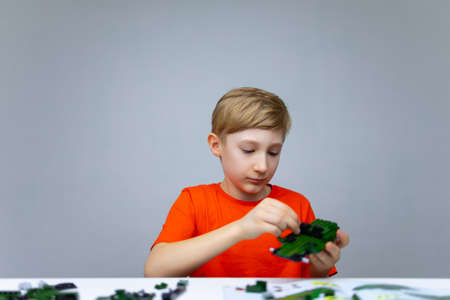a boy plays with a plastic constructor examines the instructions for assembling a model