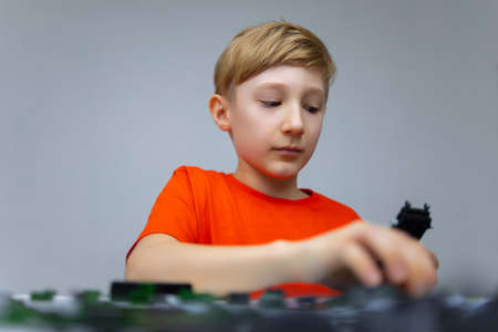 a boy plays with a plastic constructor examines the instructions for assembling a model