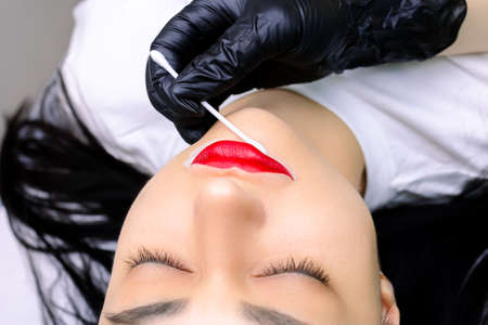 close-up of the model's lips which outline the contour with a white pencil before the permanent make-up procedureの写真素材