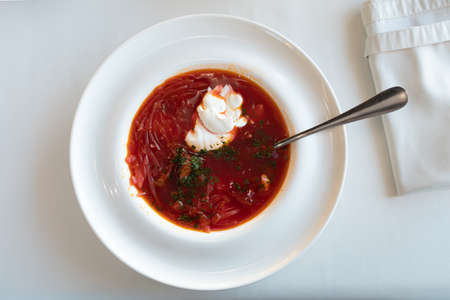 Ukrainian borsch on a snow-white tablecloth in a restaurant seasoned with sour cream