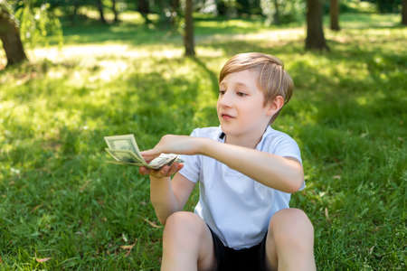 a child in the park holds dollar bills in front of him and throws them in front of himの写真素材
