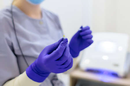 in the cosmetology room, the doctor bent over the model and perform the procedure of electrolysis removing unwanted hairs in the armpit areaの写真素材