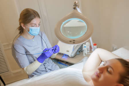 The electroepilation master sits opposite the client and prepares for the procedure for removing...