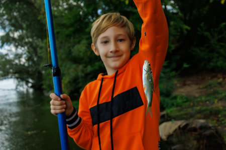 close-up of a small fish on a hook that the boy caught and holds in front of himの写真素材