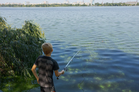 A teenager holds a fishing rod and watches a fish nibble. Sport fishing on the river in summer.の写真素材