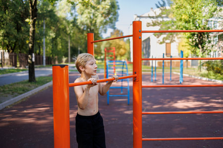 Muscular teenager stretched up his chin on the horizontal bar. Street workout on a horizontal bar in...