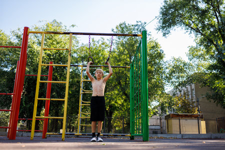 An athletic kid grabbed the rings to do a pull-up. Street workout on a horizontal bar in the school...