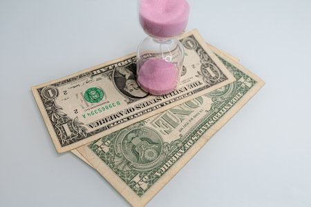 One dollar bills have hourglasses on them. The hourglass is located near the dollar bills.